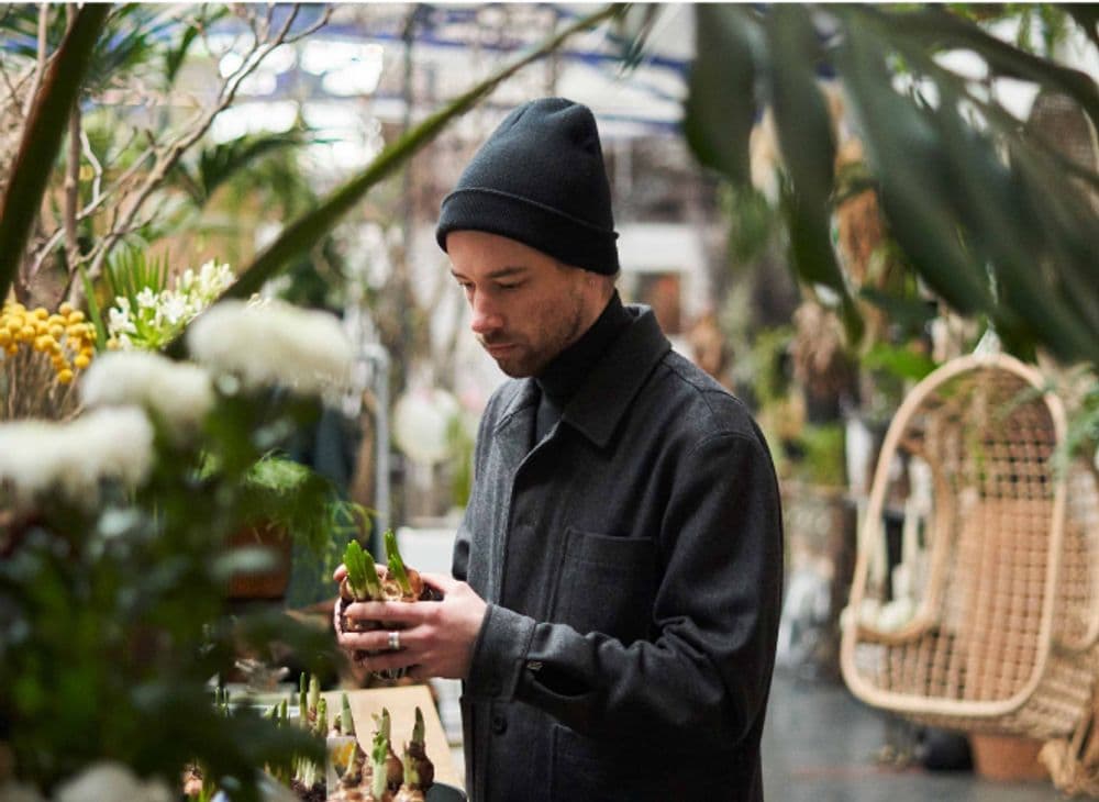A man holding a plant inside a greenhouse