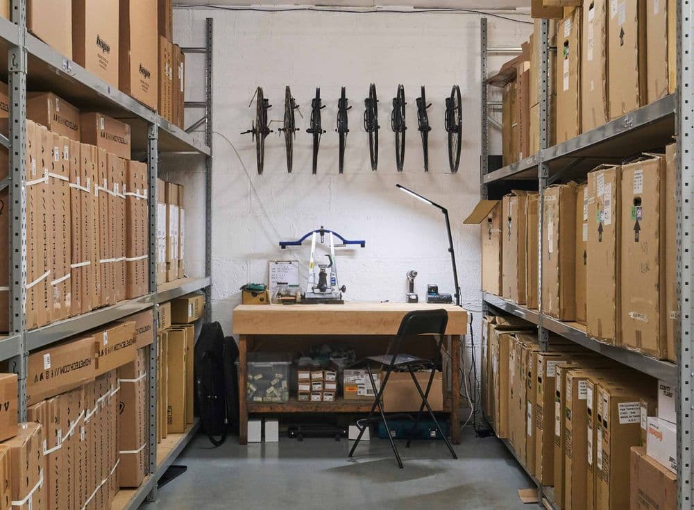 A desk situated in between two industrial shelves inside a storeroom environment