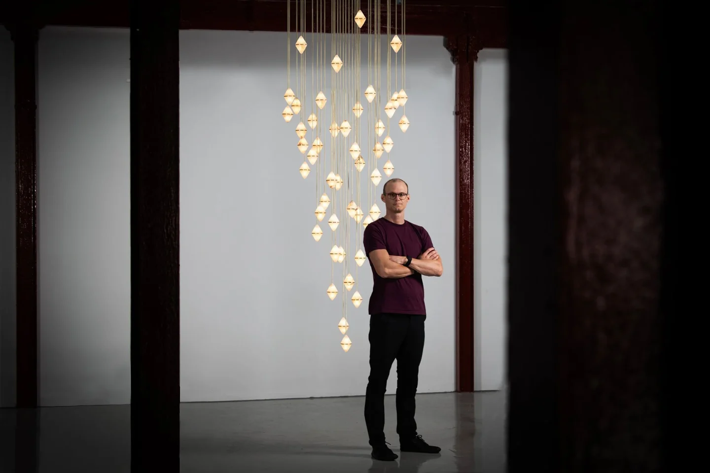 Marc wood stands in an empty studio in front of one of his feature lights.